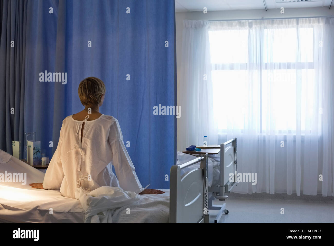 Paziente che indossa vestaglia sul letto di ospedale Foto Stock