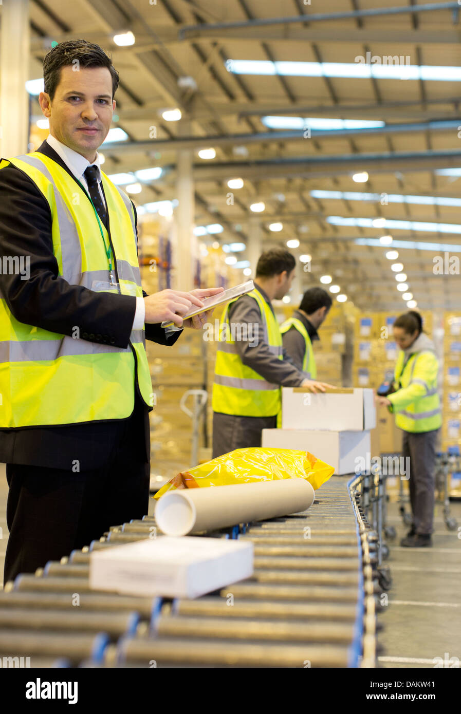 Lavoratori controllo pacchetti sul nastro trasportatore in magazzino Foto Stock