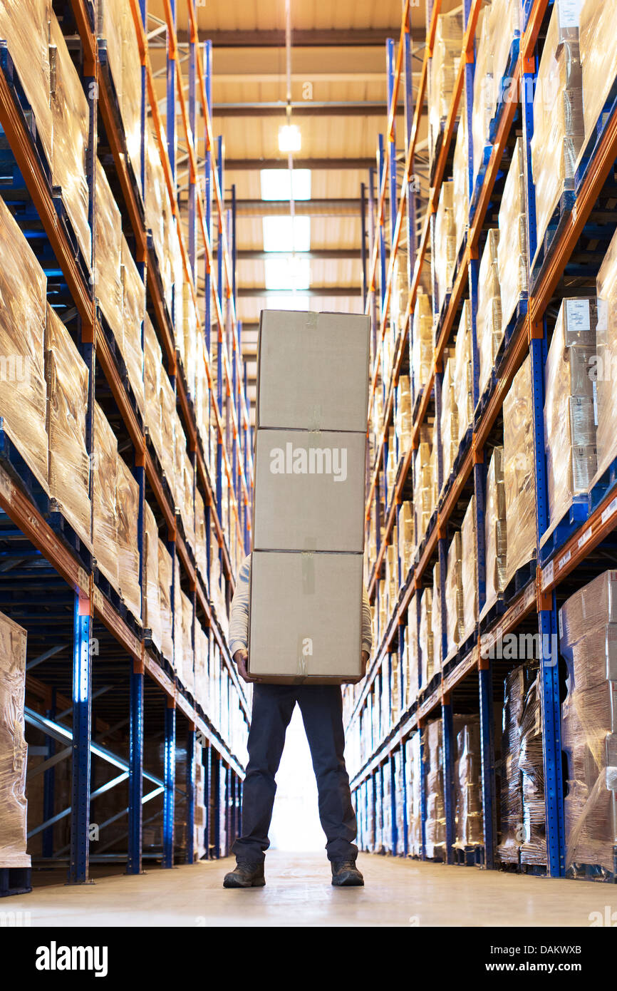 Lavoratore di scatole di contenimento in magazzino Foto Stock