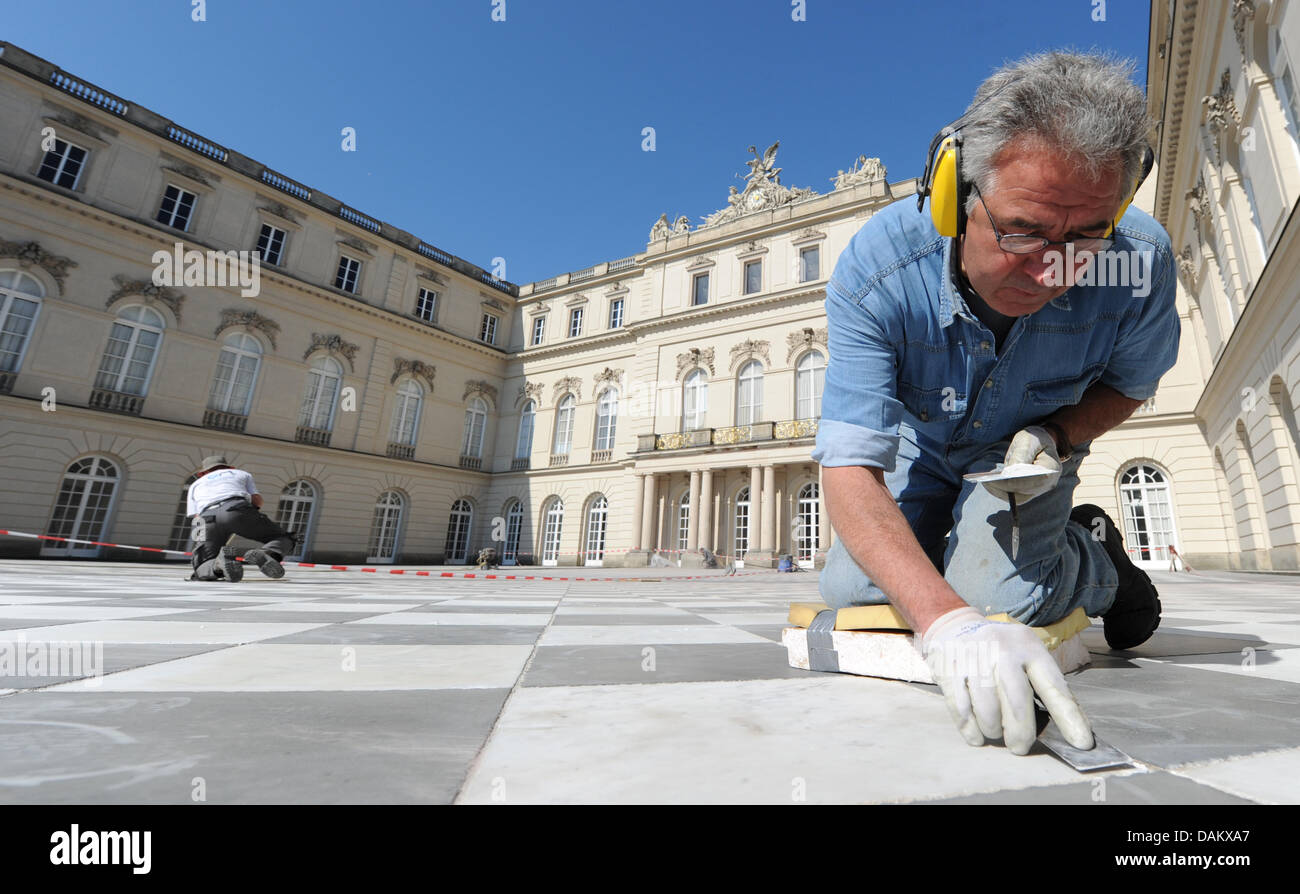 Un uomo lavora sui giunti tra piastrelle presso il cortile di Palazzo Herrenchiemsee Palace di Herrenchiemsee, Germania, 05 maggio 2011. La vita e la morte tragica del monarca bavarese Ludwig II sono presentate in modo cronologicamente organizzata una mostra con ancora presenta invisibili. Foto: Marc Mueller Foto Stock