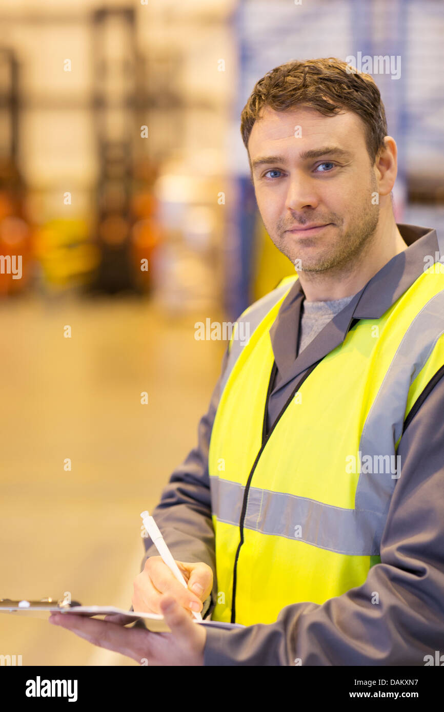 Lavoratore utilizzando gli appunti in magazzino Foto Stock