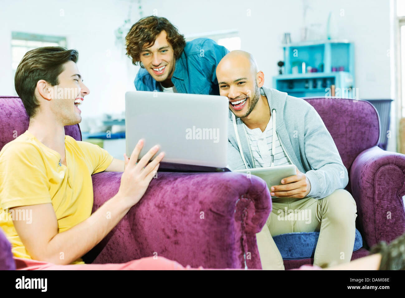 Gli uomini utilizzando laptop insieme in salotto Foto Stock