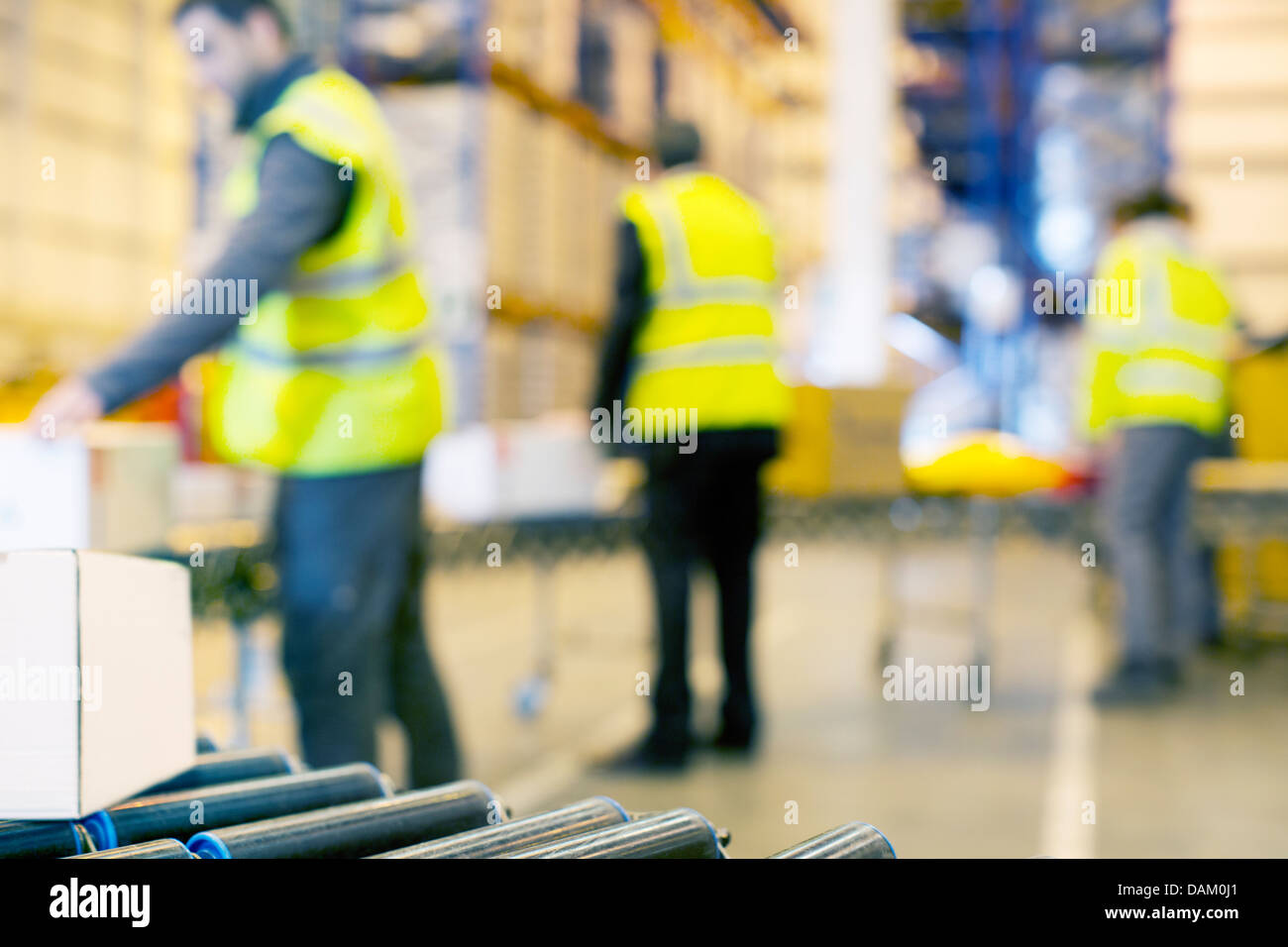 Lavoratori esaminando scatole sul nastro trasportatore in magazzino Foto Stock