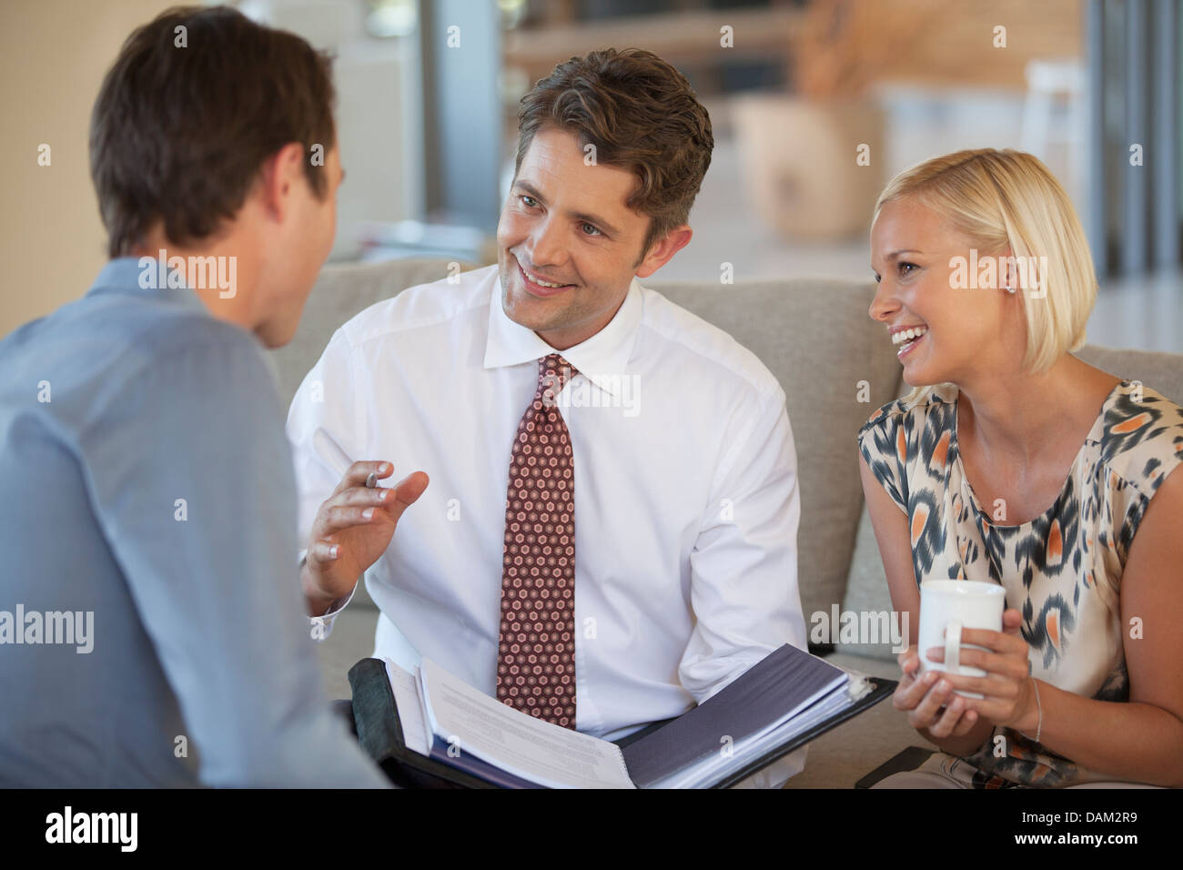 Advisor finanziario di parlare al giovane sul divano Foto Stock