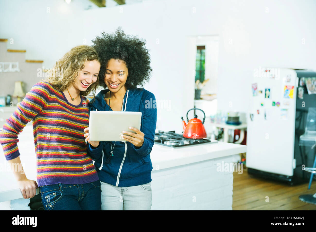 Le donne che usano i computer tablet in cucina Foto Stock