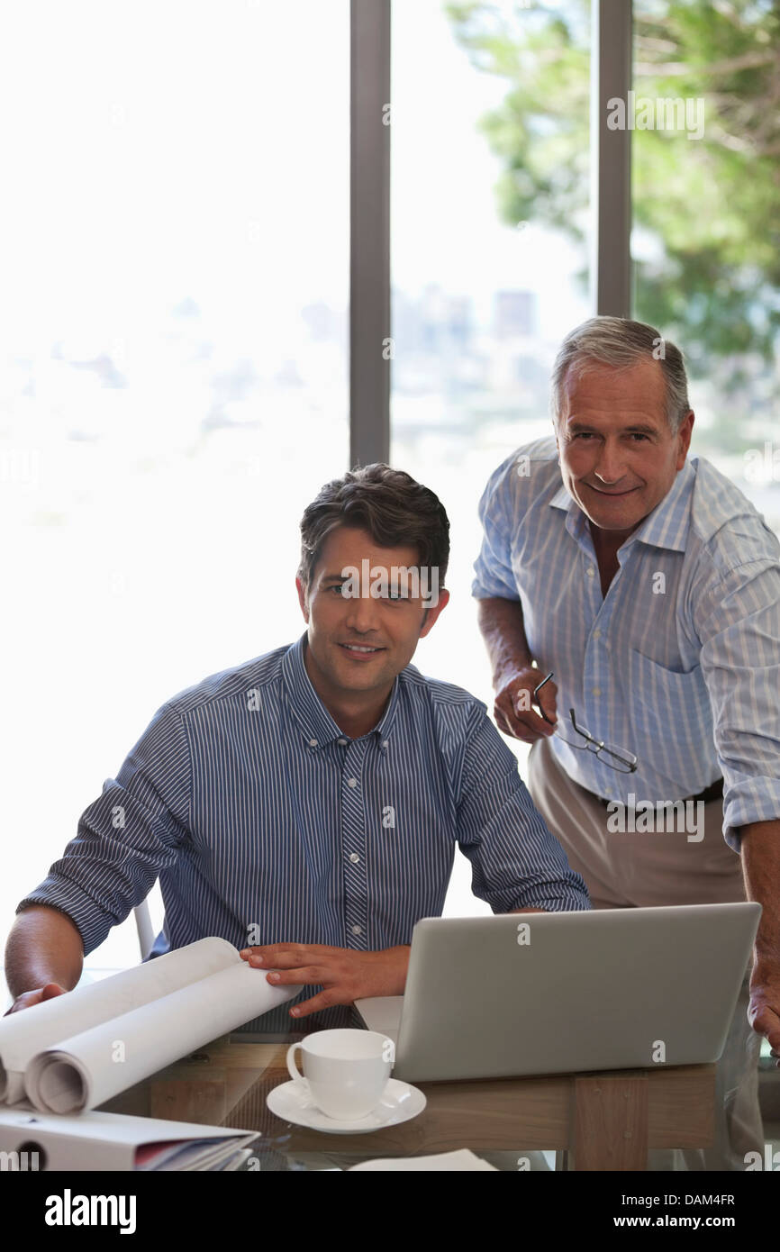 Uomo più anziano e più giovane uomo che lavora insieme alla scrivania Foto Stock