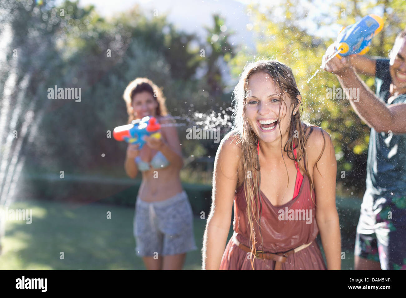 Amici a giocare con le pistole di acqua nel cortile posteriore Foto Stock