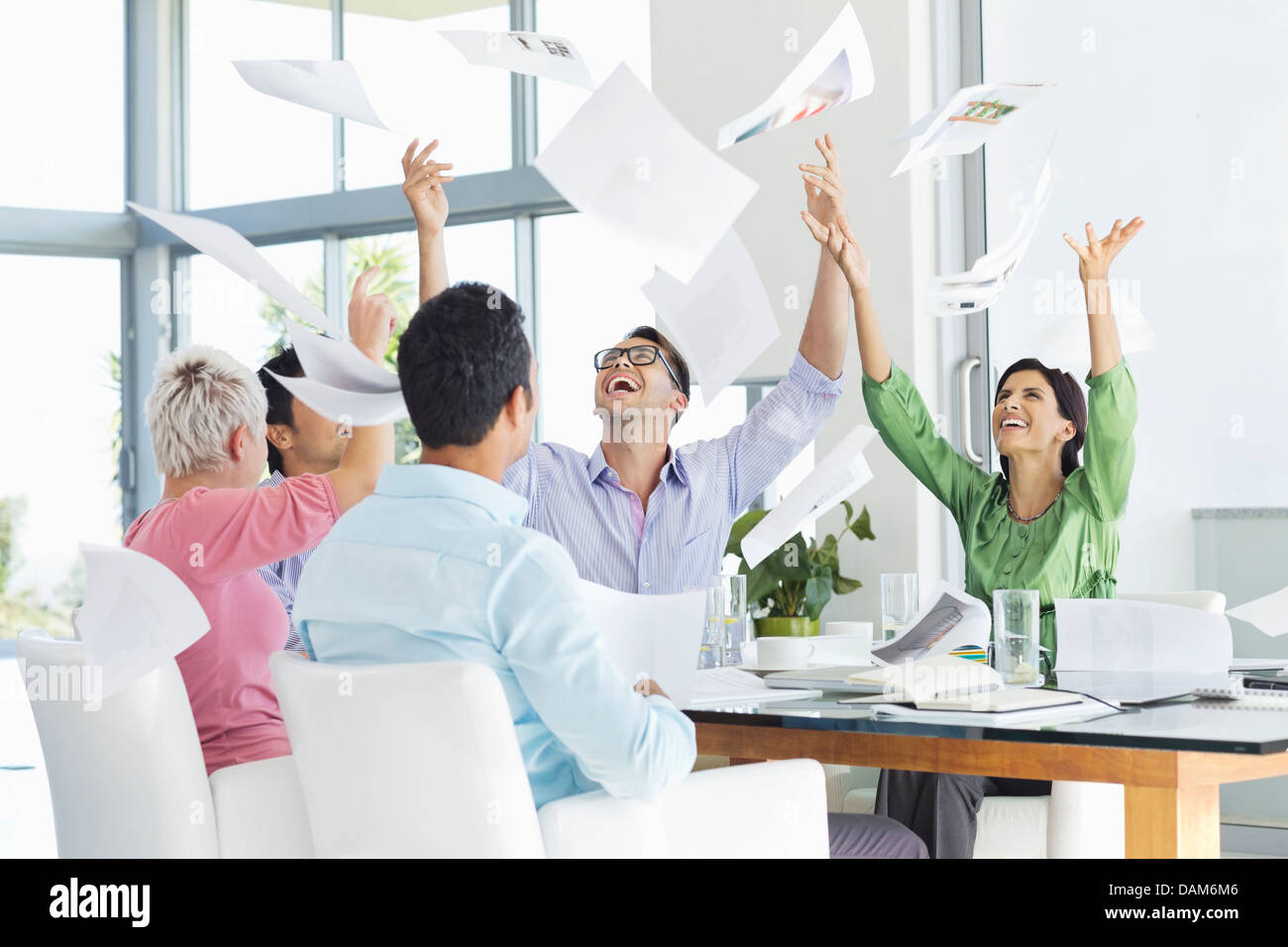 La gente di affari tossing papers in aria in riunione Foto Stock