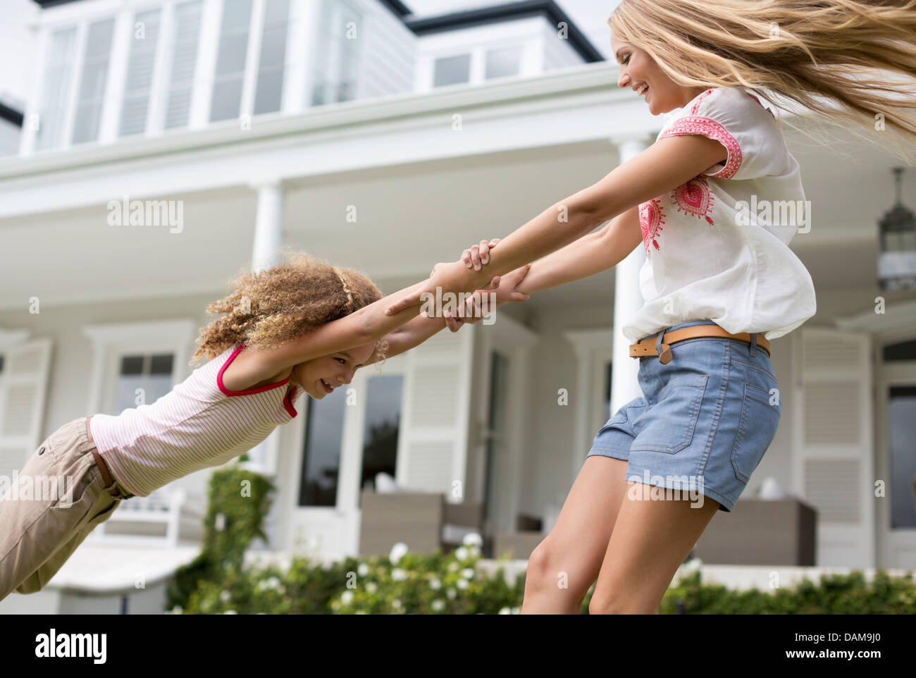 Madre e figlia giocando fuori casa Foto Stock