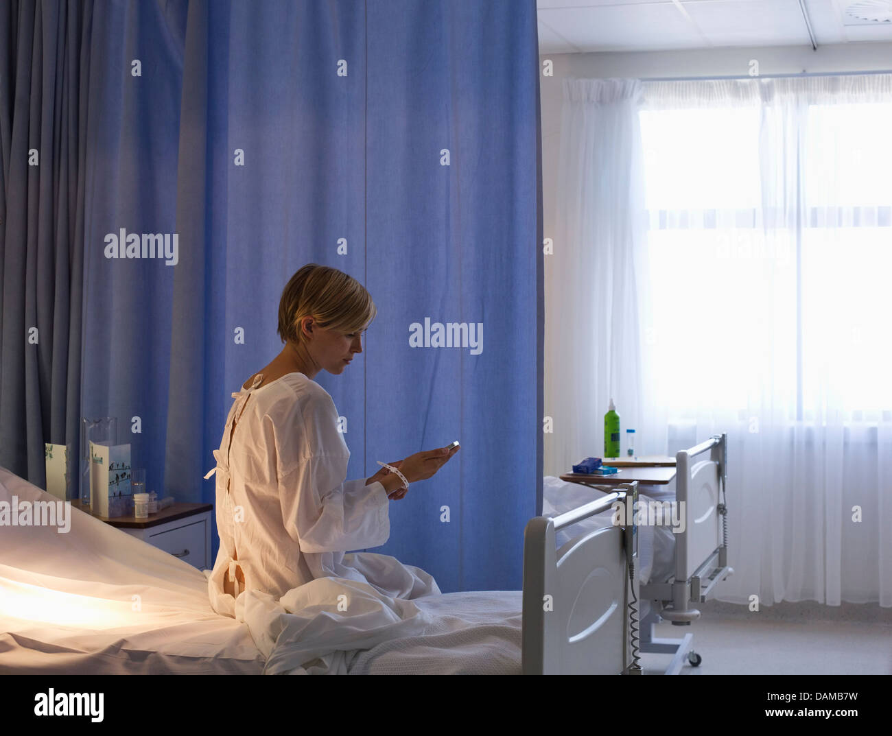 Paziente utilizzando il telefono cellulare nel letto di ospedale Foto Stock
