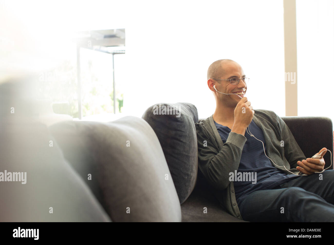 Uomo che parla su auricolare sul divano Foto Stock