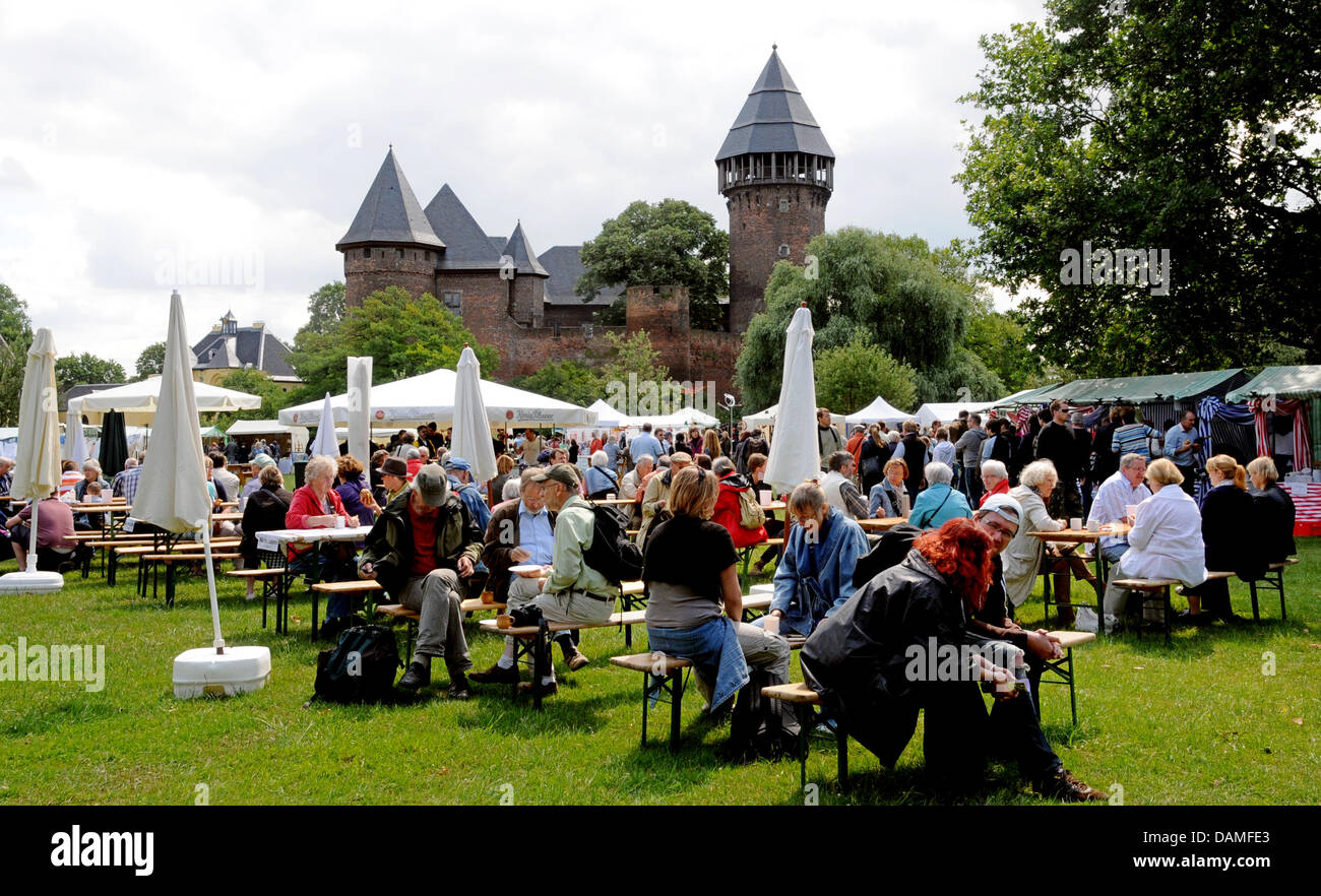I visitatori del Flachsmarkt (artigianato storico mercato) sedersi in un campo di fronte Linn castello in Krefeld, Germania, 11 giugno 2011. Il tradizionale Flachsmarkt ha iniziato a Krefeld, con più di 300 artigiani e artisti, cavalieri e tornei medievali, giocoleria e artigianato, e più di centomila persone frequentano l'evento di tre giorni sul fine settimana di Pentecoste. Foto: Horst Ossinger Foto Stock