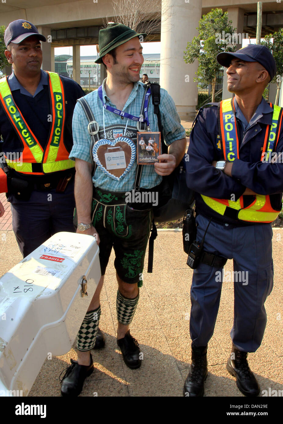 Un musicista di 'Koitabach Musi " gruppo di musica tradizionale da Garmisch-Partenkirchen, Germania, sorge accanto ai poliziotti con i suoi strumenti in aeroporto a Durban, Sud Africa, 5 luglio 2011. Comitato Olimpico Internazionale CIO deciderà sulla posizione delle olimpiadi invernali 2018 il 6 luglio 2011. Monaco di Baviera compete nei confronti della Corea del Sud Pyeongchang e francese di Annecy. Foto: STEPH Foto Stock