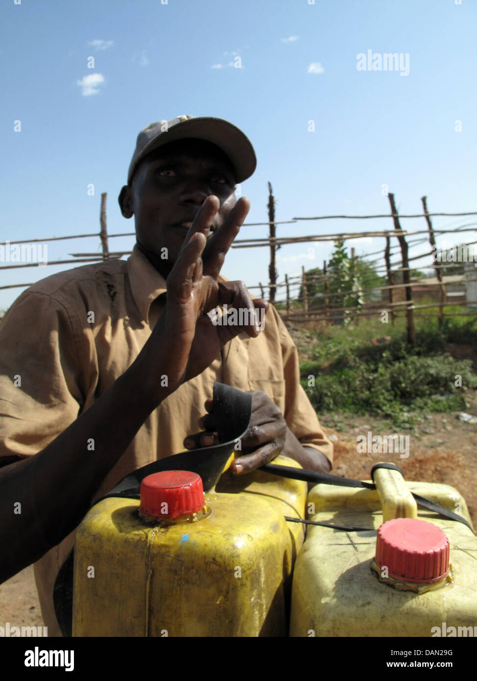 Water carrier Robert Malikeye gesti dopo che egli ha riempito i barattoli con acqua potabile e legato alla sua moto a Juba nel sud Sudan, 2 aprile 2011. Il 30-anno-vecchio dall Uganda non ha preoccupazioni per il futuro per ora. Egli acquista un centinaia di litri di acqua in 10 litri di taniche per quattro libbre ciascuno. Allora egli li trasporta tediously attraverso il brillare strade sulla sua moto. Foto: EVA KR Foto Stock