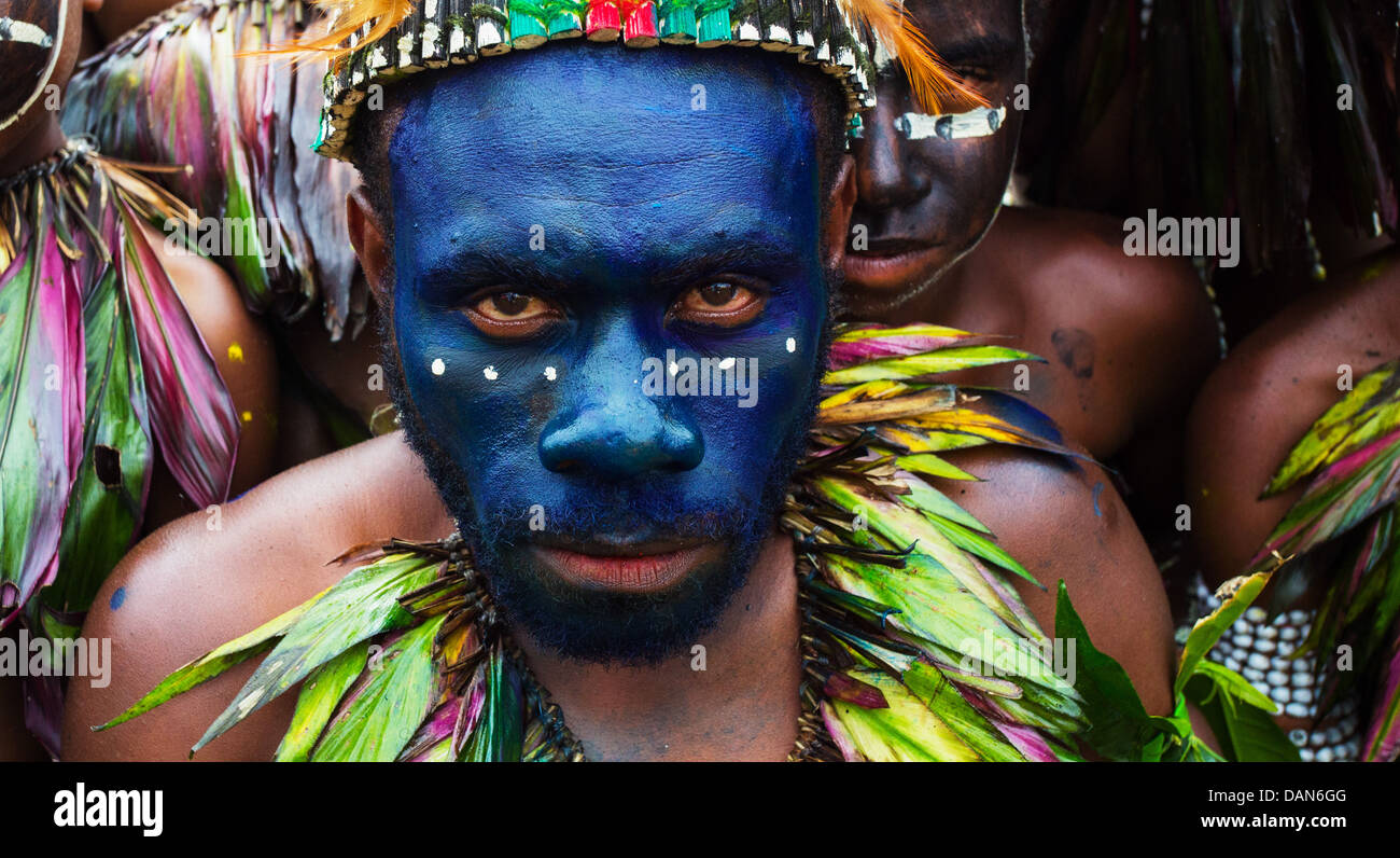 Tribal l uomo con il suo volto dipinto in vernice blu e indossa una collana di piume presso il festival di Goroka in Papua Nuova Guinea Foto Stock