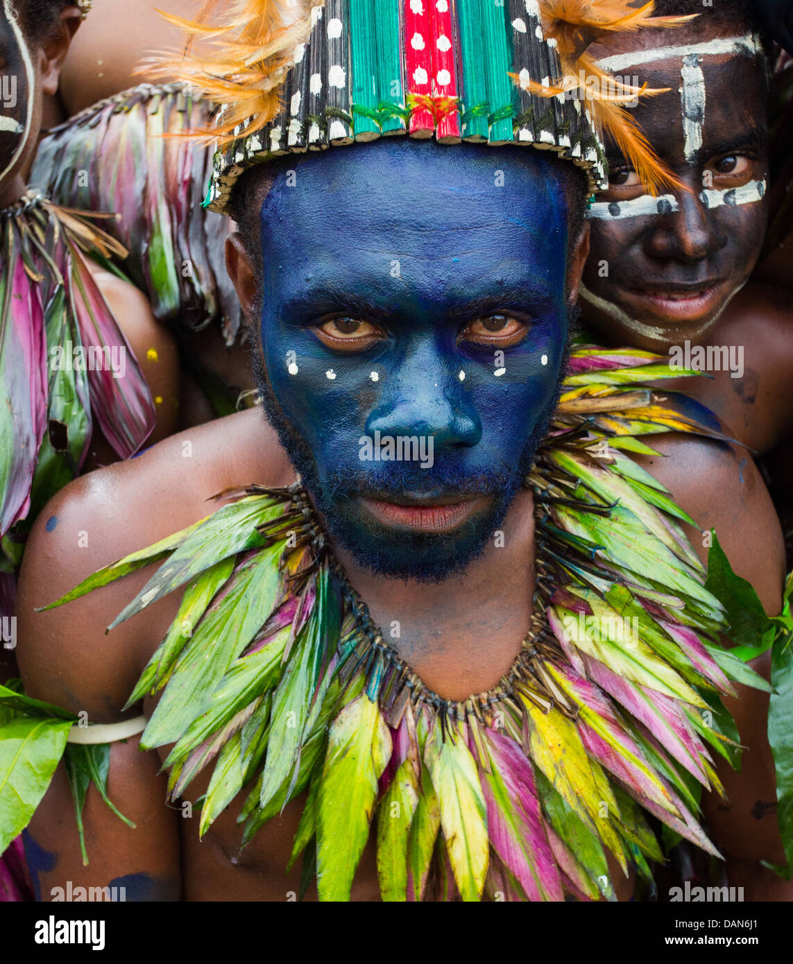 Tribal l uomo con il suo volto dipinto in vernice blu e indossa una collana di piume presso il festival di Goroka in Papua Nuova Guinea Foto Stock