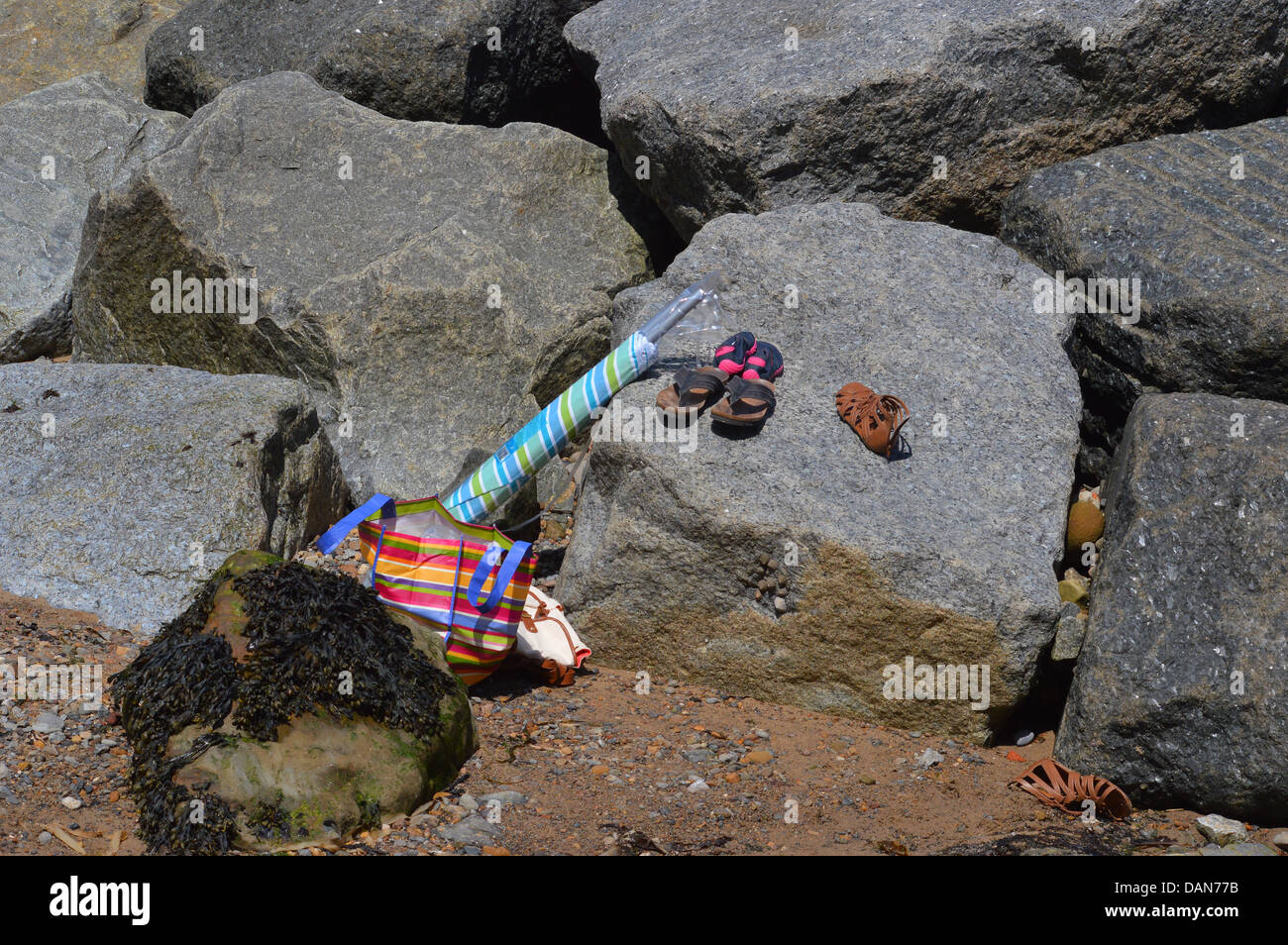 Ombrello , bag , scarpe e sandali a sinistra su rocce sulla spiaggia Staithes Foto Stock