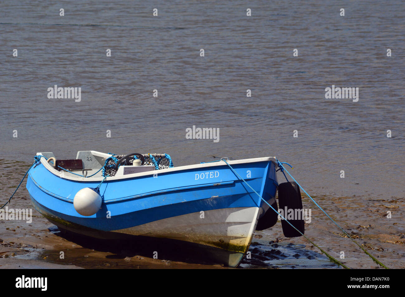 Piccolo Blu e bianco imbarcazione attraccata con corde sulla spiaggia Staithes , sulla sabbia con il mare in background Foto Stock