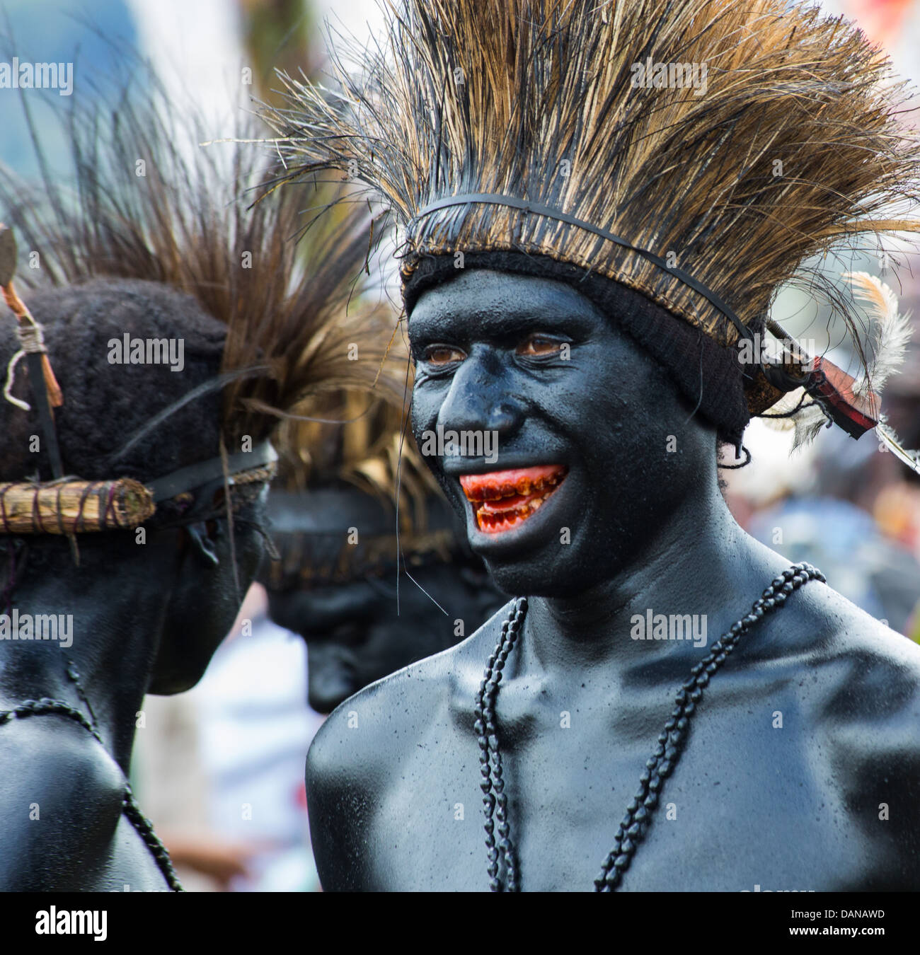 Gli uomini verniciato nero lucido e indossando un copricapo di erba a Goroka show in Papua Nuova Guinea Foto Stock