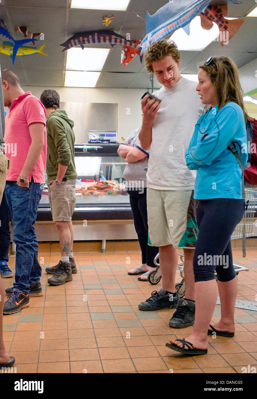 I clienti che acquistano il pesce fresco e i granchi a New Sagaya del mercato di Midtown, Anchorage, Alaska, Stati Uniti d'America. Pesce Finto appesi al soffitto. Foto Stock