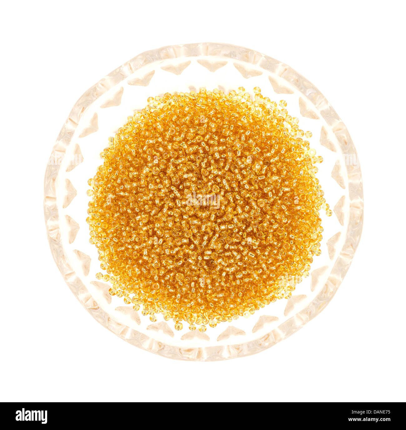 Vista dall'alto di una ciotola con oro piccole perle di vetro su uno sfondo bianco. Foto Stock