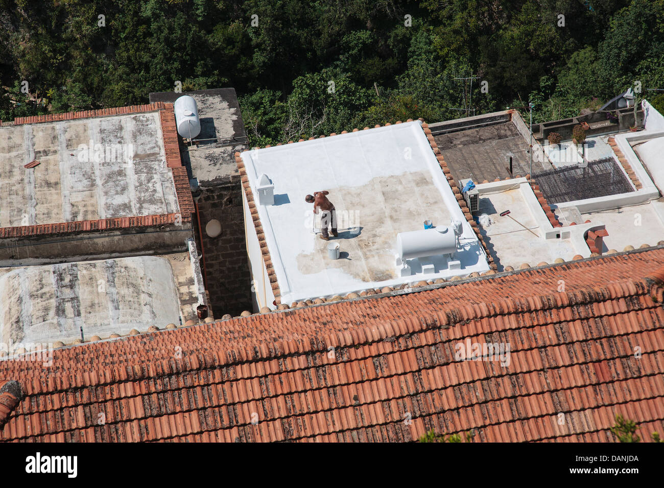 Uomo di verniciatura di un tetto di casa nel villaggio di Positano, Italia. Foto Stock