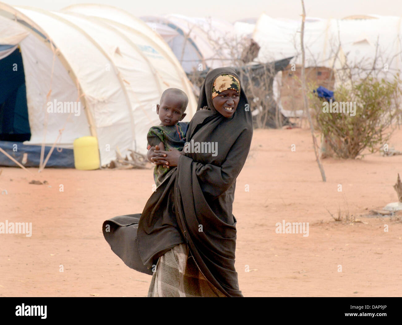 Una donna somala porta il suo bambino attraverso interminabili file di tende in un campo di rifugiati di Dadaab, Kenya 4 agosto 2011. Somalia e parti del Kenya è stata colpita da una delle peggiori le bozze e carestie in sei decenni, più di 350 000 profughi hanno trovato rifugio in mondi più grande campo di rifugiati. Foto: Boris Roessler Foto Stock