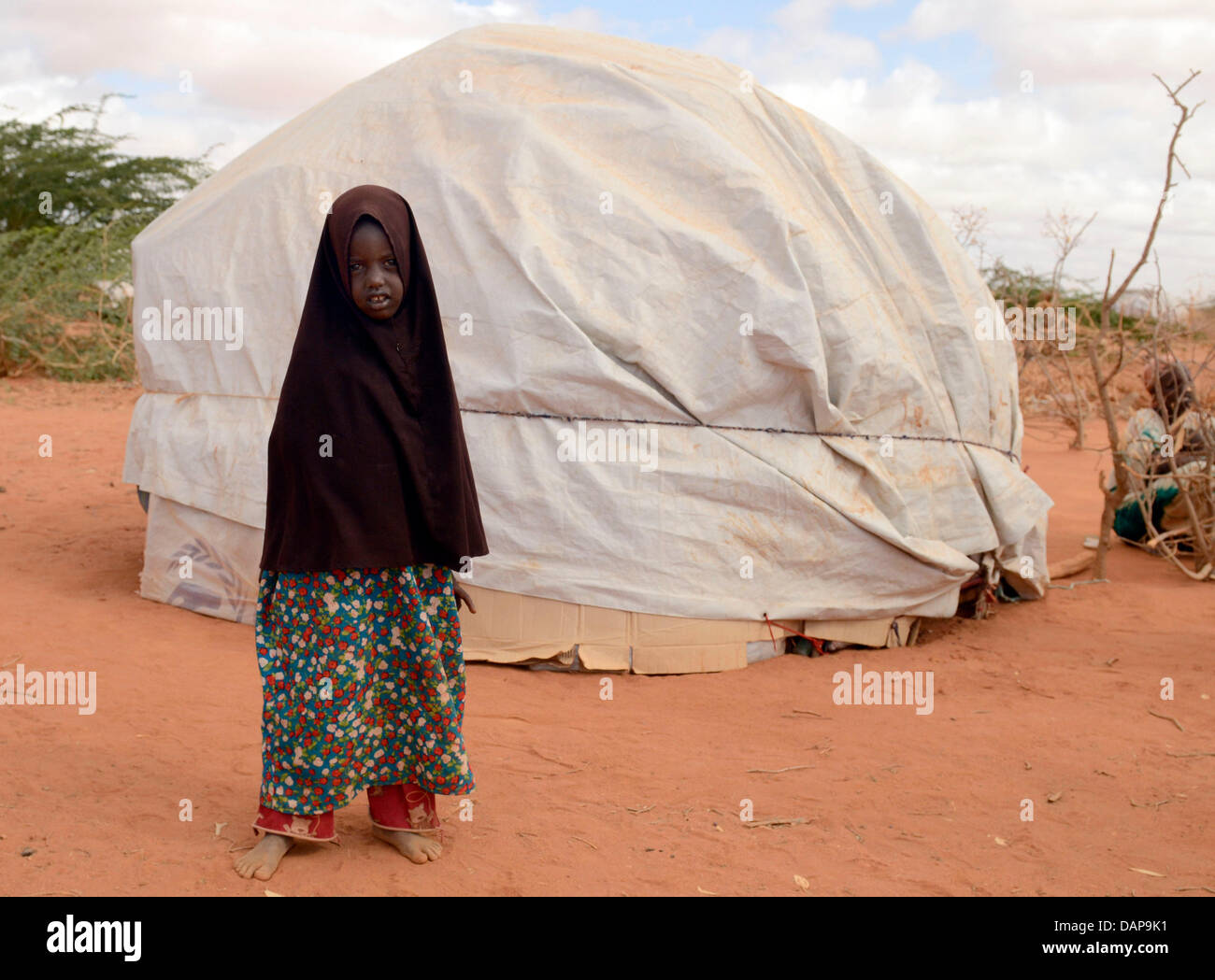 Tradizionalmente un abiti ragazza somala sorge fuori la sua tenda in un campo di rifugiati di Dadaab, Kenya 4 agosto 2011. Somalia e parti del Kenya è stata colpita da una delle peggiori le bozze e carestie in sei decenni, più di 350 000 profughi hanno trovato rifugio in mondi più grande campo di rifugiati. Foto: Boris Roessler Foto Stock