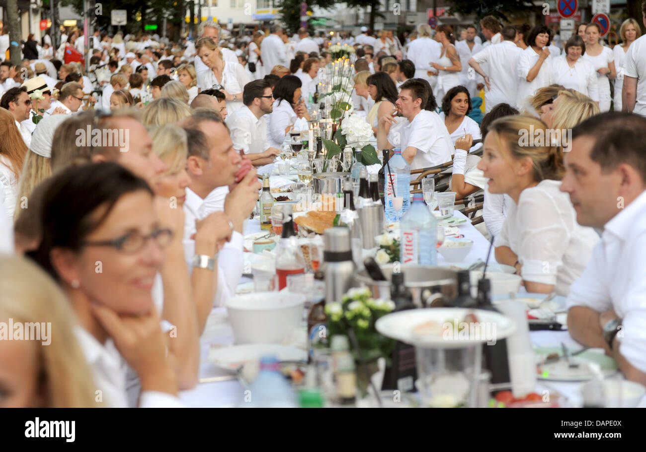 I partecipanti del secondo 'White dinner' sedere a lunghi tavoli da pranzo al Osterstrasse ad Amburgo, Germania, 13 agosto 2011. Più di un migliaio di persone vestite di bianco vestiti mangiato insieme al White dinner in Amburgo. L'idea in precedenza deriva da Parigi, Francia. Foto: Marcus Brandt Foto Stock