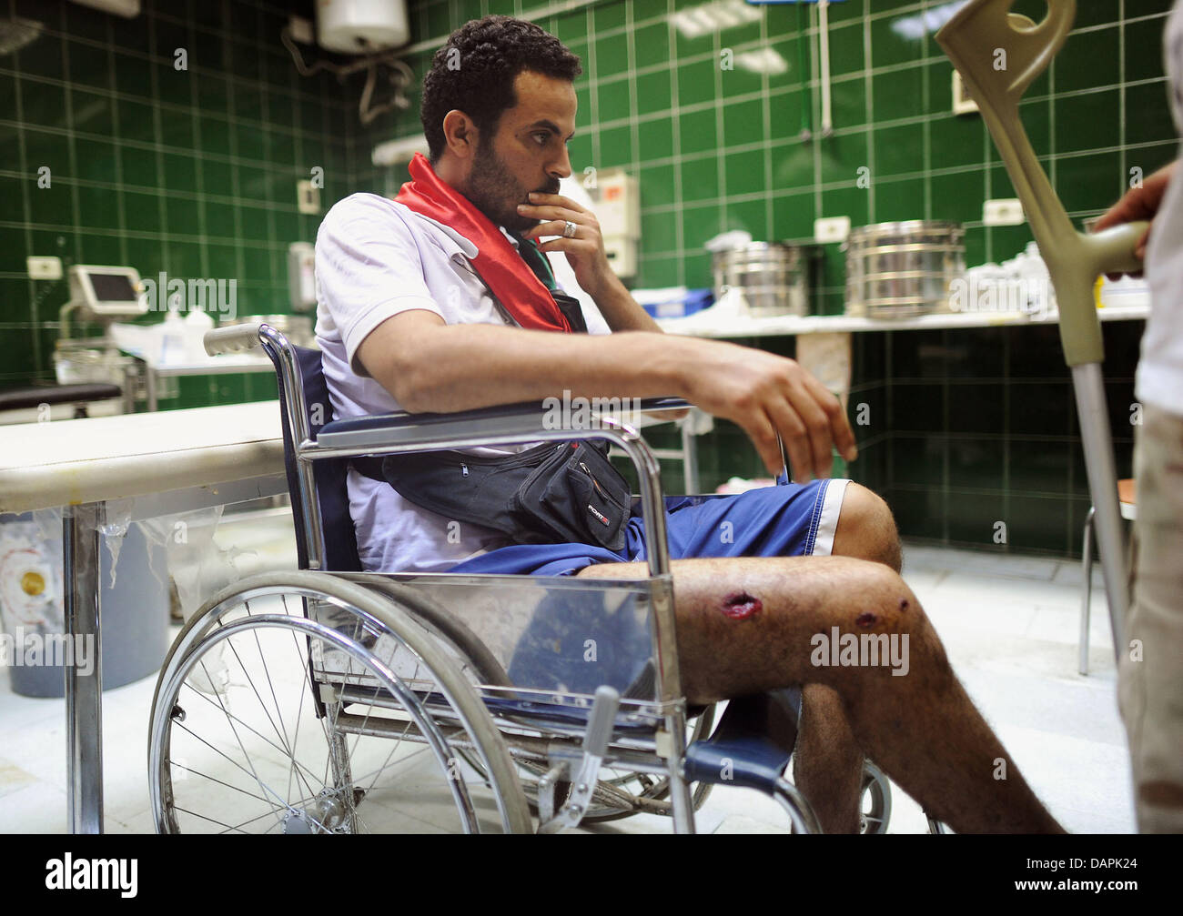 Ein Verwundeter Mann sitzt am Mittwoch (24.08.2011) in einem Rollstuhl in einem Krankenhaus in al Sawija, Libyen, rund 50 chilometro westlich der Hauptstadt Tripolis. Regime di Das des Diktators libyschen Gheddafi ist am Ende, doch trotz der Siegesfeiern der Rebellen kämpfen seine letzten Getreuen erbittert gegen den Untergang. In Tripolis und anderen Orten Libyens lieferten sich Aufstä Foto Stock