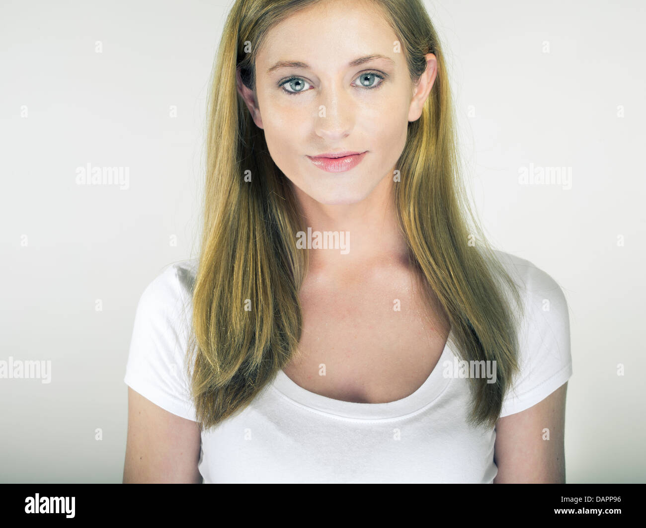 Bionda e giovane donna caucasica in t-shirt bianco su bianco di sfondo per studio sorridente in telecamera Foto Stock