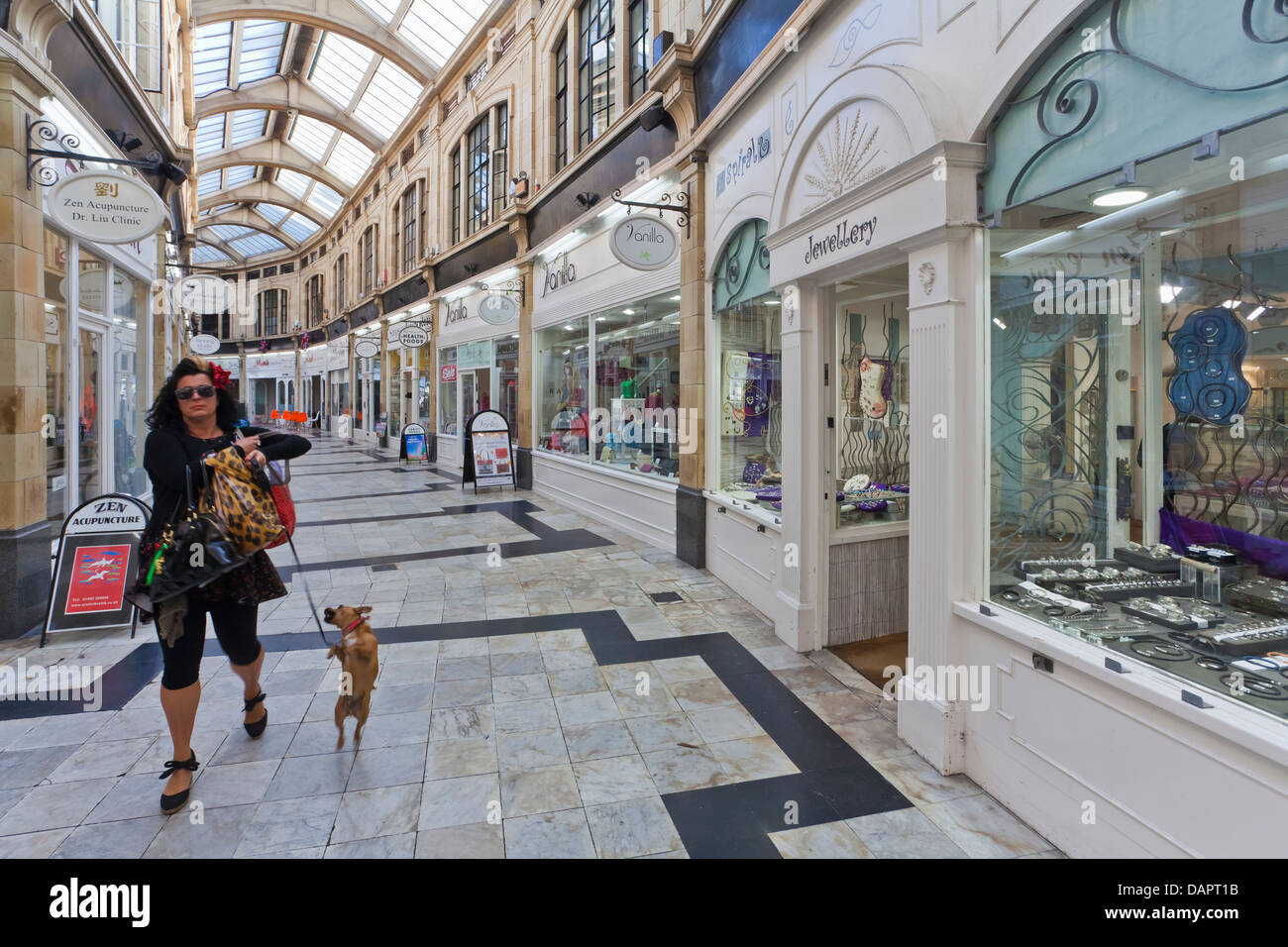 Inghilterra, Sussex, Worthing, Donna con cane a piedi a Royal Arcade Foto Stock