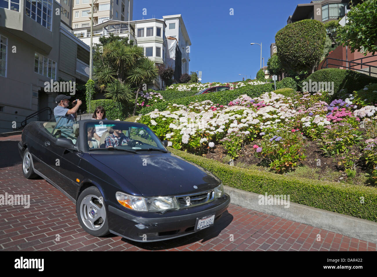 Quattro persone in autovettura convertibile scendendo Lombard Street di San Francisco in California Foto Stock