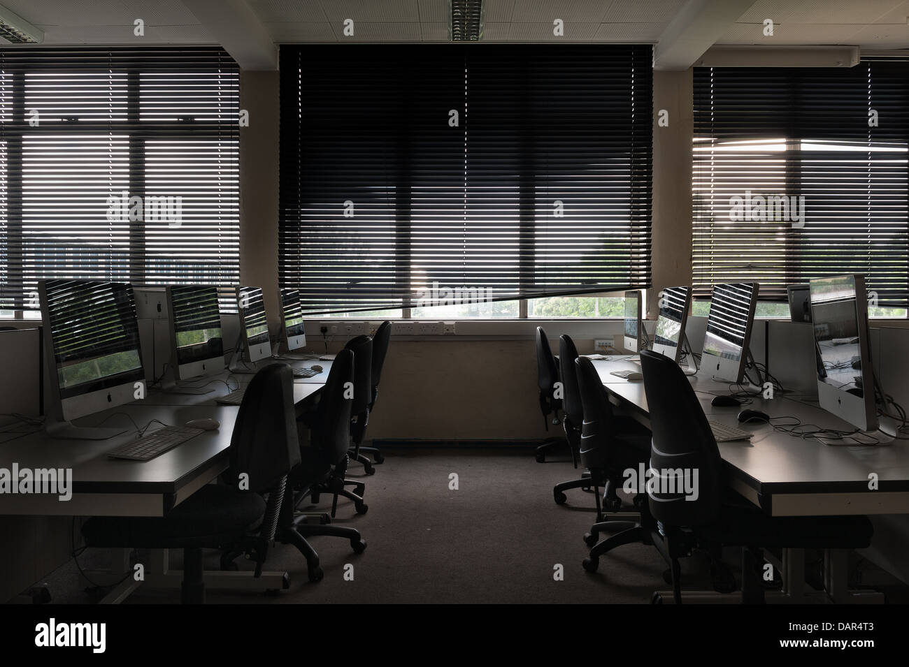 La fine della scuola o college come sappiamo che le righe di computer nel buio di una classe molto precedentemente utilizzato per ora in attesa di essere utilizzati Foto Stock