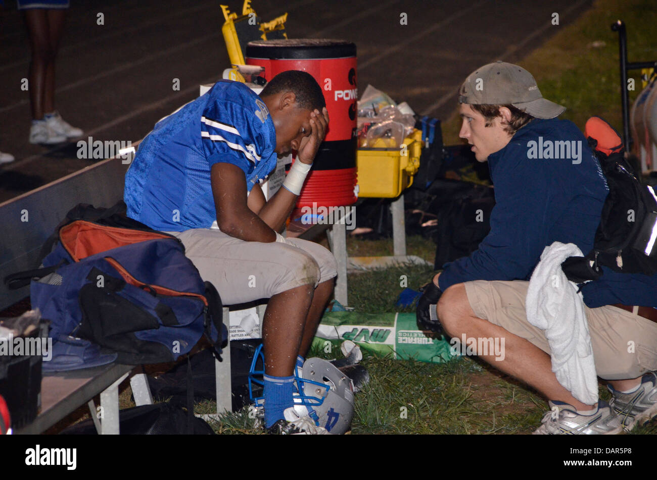 Medic interrogando il giocatore che è stato ferito e rimosso da una scuola di gioco del calcio in MD Foto Stock