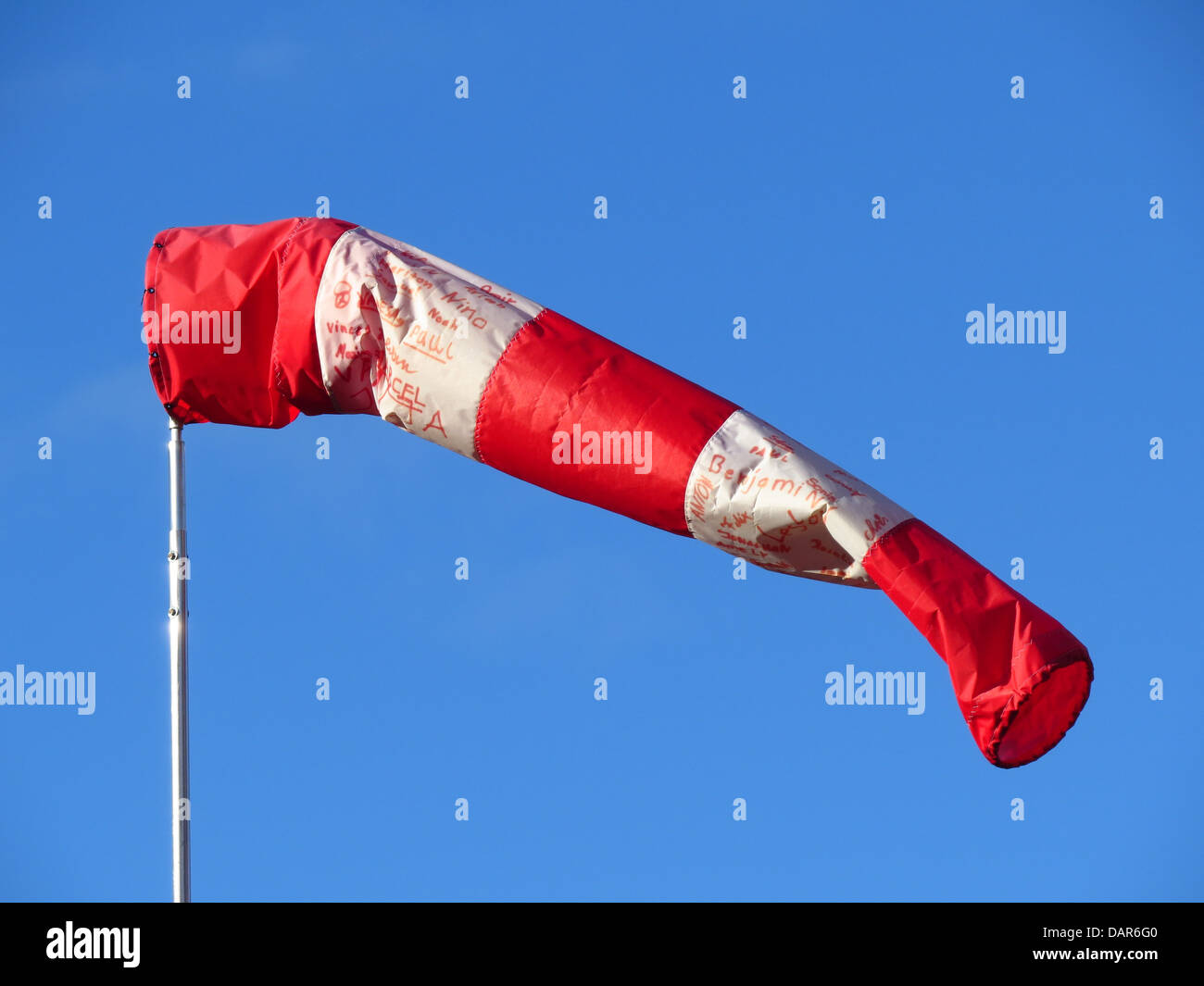 La calza da vento è uno strumento fondamentale utilizzato negli aeroporti e nei campi di aviazione per determinare la direzione e la velocità del vento. Questo airbag a strisce rosse e bianche aiuta i piloti a valutare le condizioni del vento, garantendo operazioni di volo sicure. Funge da indicatore meteorologico semplice ma cruciale per la sicurezza e la navigazione aerea. Foto Stock