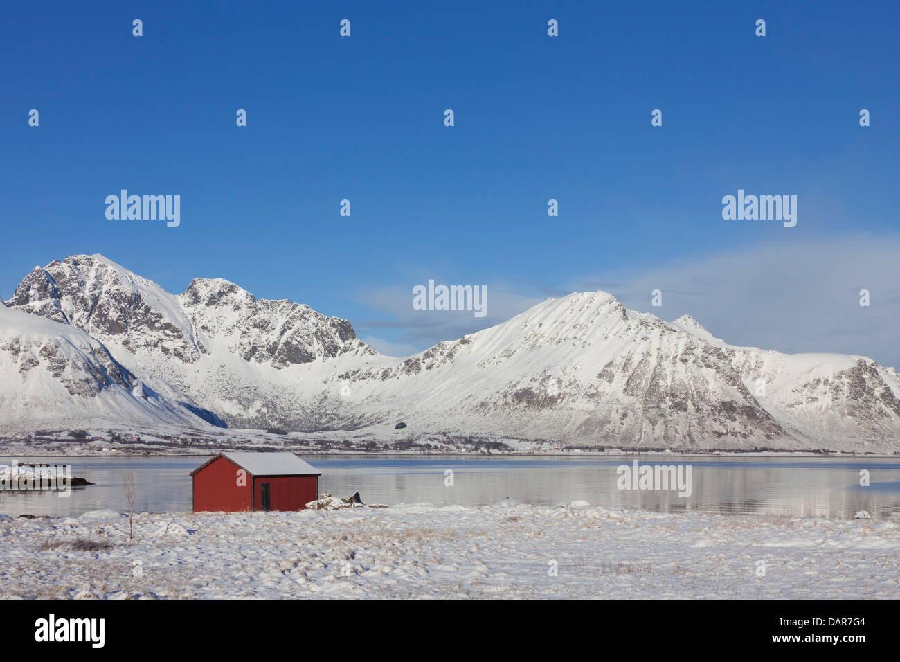 Rosso isolato in legno cabina rorbuer lungo la costa nella neve in inverno, Isole Lofoten, Nordland, Norvegia e Scandinavia Foto Stock