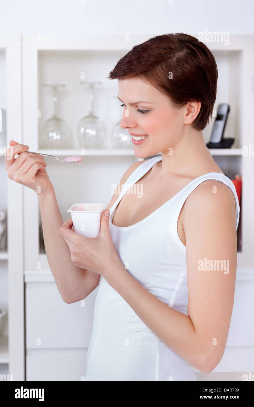 Giovane bella donna mangiare yogurt come la colazione o uno spuntino Foto Stock