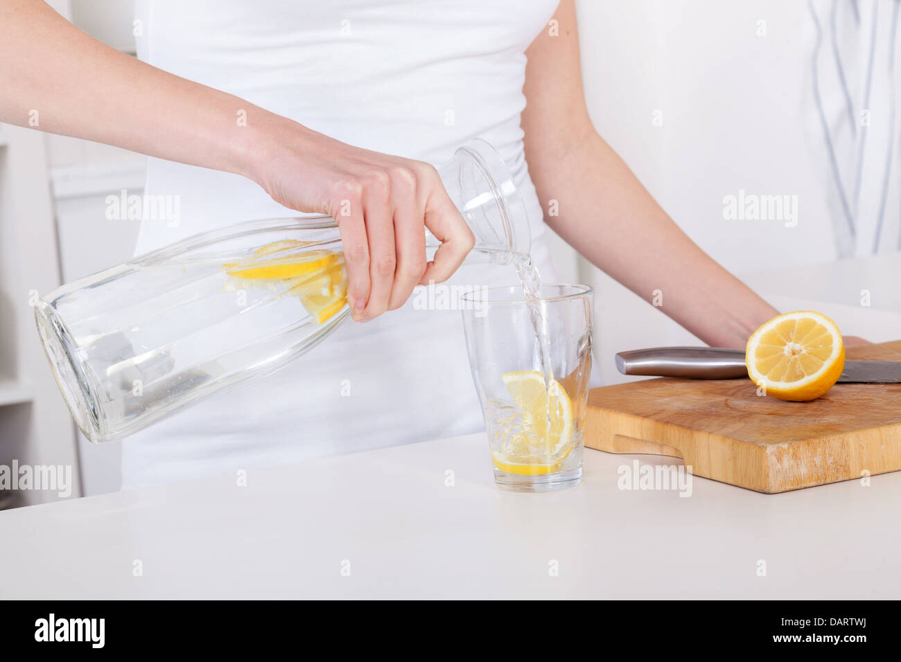 Giovane donna preparare e bere la limonata nella sua cucina moderna Foto Stock