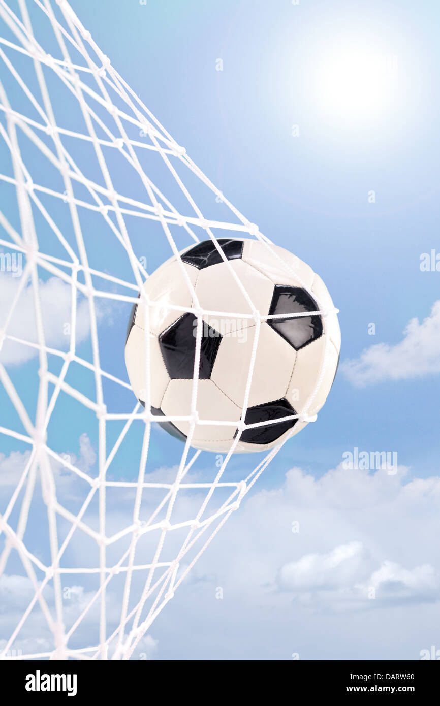 Pallone da calcio in un gol contro il cielo nuvoloso Foto Stock