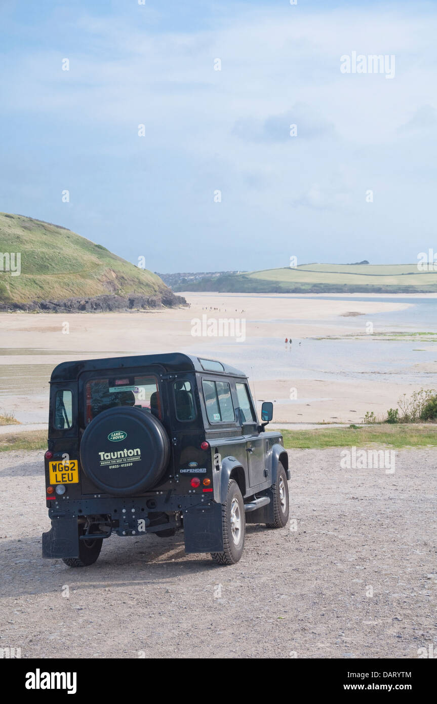 Land Rover - Defender; con Daymer Bay beach come sfondo. Cornovaglia, Inghilterra, Regno Unito. Foto Stock