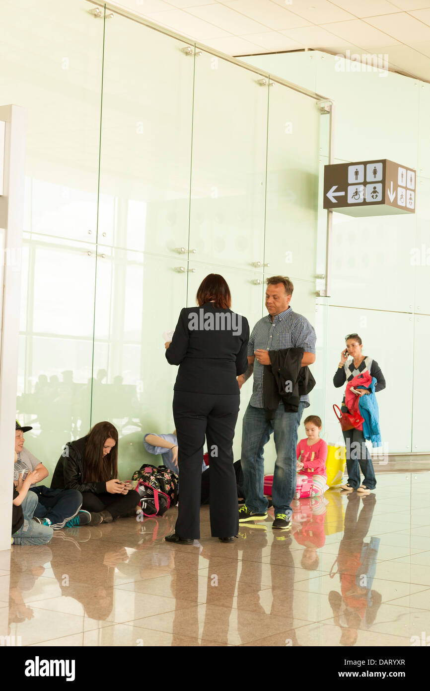 I passeggeri seduti sul pavimento esterno wc in attesa in aeroporto Foto Stock