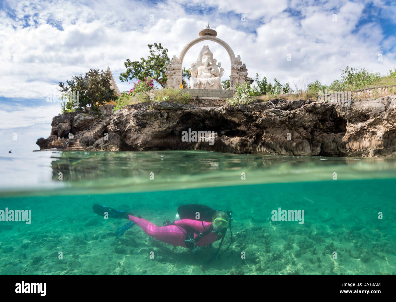 A livello diviso Vista del biondo sub femmina esplorazione subacquea al fianco di isola tropicale con tempio in background Foto Stock