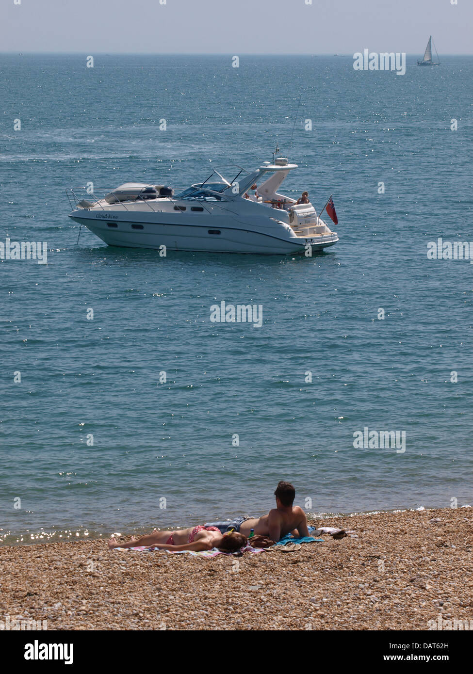 Matura a prendere il sole sulla spiaggia con la motonave attraccata al mare, Devon, Regno Unito 2013 Foto Stock