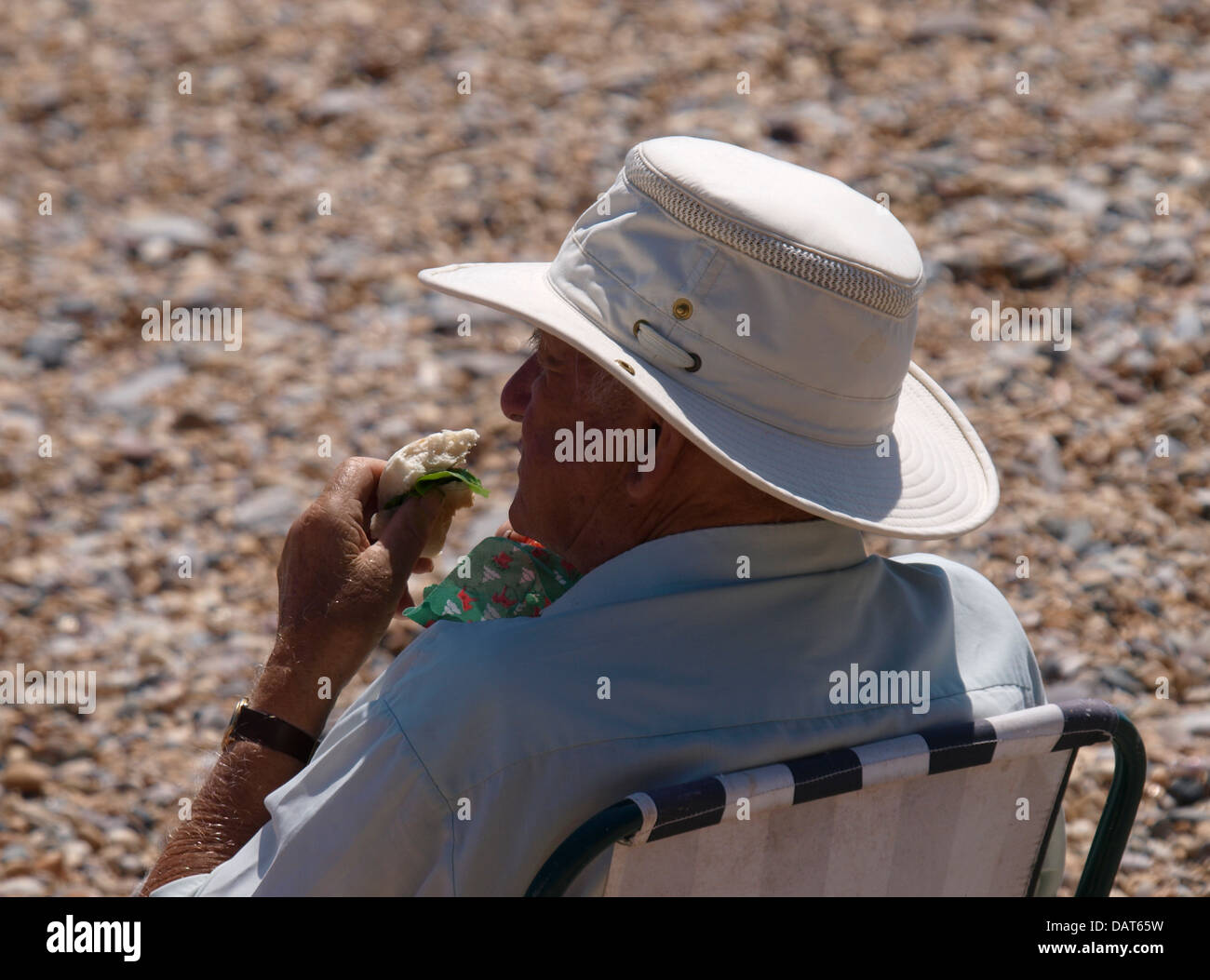 Il vecchio uomo mangiare panino in spiaggia, Devon, Regno Unito 2013 Foto Stock