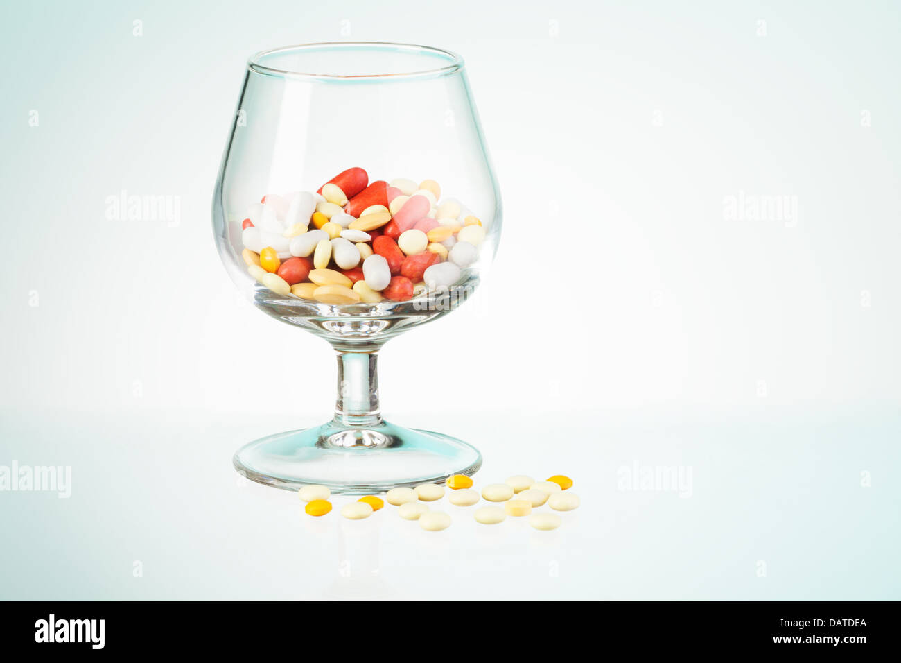 Problema potabile allegoria rappresentata da whisky classe piena di farmaci e pillole sparsi sul tavolo Foto Stock