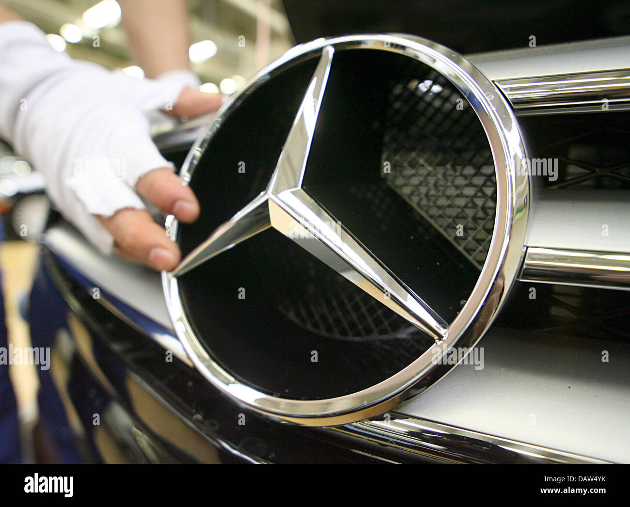 Un dipendente di costruttore DaimlerChrysler AG indossando i guanti di cotone bianco fissa la famosa stella a tre punte con un anello normale Mercedes Benz logo sulla griglia del radiatore di una Mercedes Benz Classe S berlina presso lo stabilimento della società in Sindelfingen, Germania, Venerdì, 02 febbraio 2007. DaimlerChrysler impiega 29,900 persone a livello mondiale la sua più grande impianto di produzione in Sindelfingen, che da Foto Stock