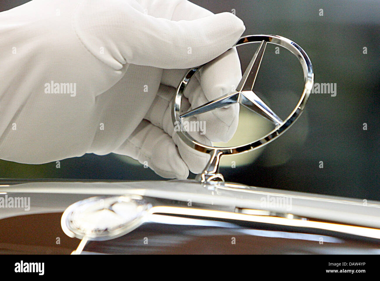 Un dipendente di costruttore DaimlerChrysler AG indossando i guanti di cotone bianco fissa la famosa stella a tre punte con un anello normale Mercedes Benz logo sul cofano motore di una Mercedes Benz Classe S berlina presso lo stabilimento della società in Sindelfingen, Germania, Venerdì, 02 febbraio 2007. DaimlerChrysler impiega 29,900 persone a livello mondiale la sua più grande impianto di produzione in Sindelfingen, che dai Foto Stock