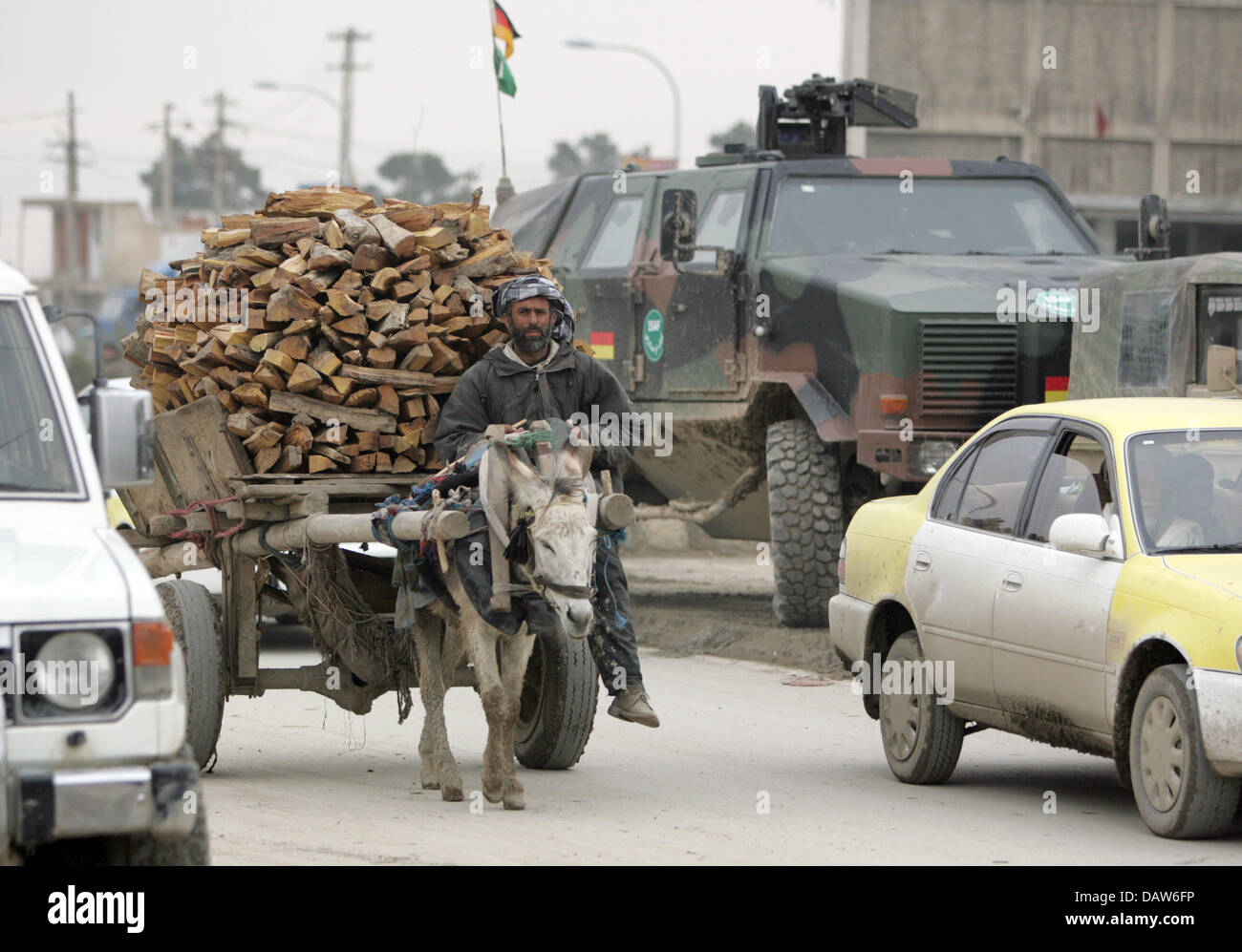 Un asino carrello pesantemente caricato con legno passa un 'Dingo' veicolo blindato tedesco del contingente Isaf su strade trafficate di Mazar-i-Scharif in Afghanistan, Martedì, 20 febbraio 2007. Foto: Rainer Jensen Foto Stock