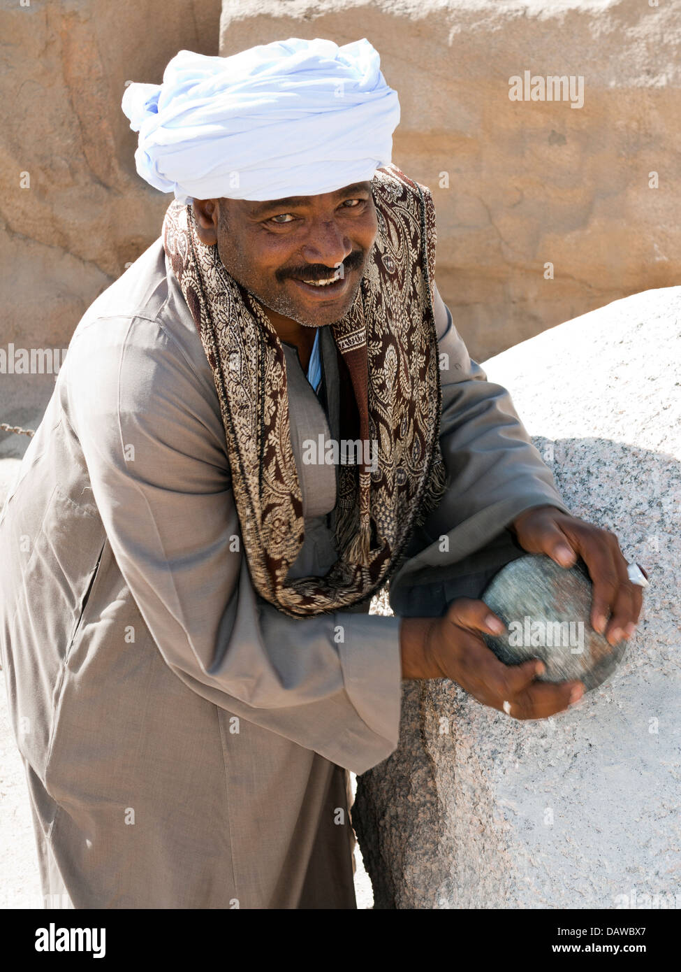 Custode holding Dolerite martello attrezzo di pietra in corrispondenza del sito dell'Obelisco incompiuto, Northern cave, Aswan, Egitto Foto Stock